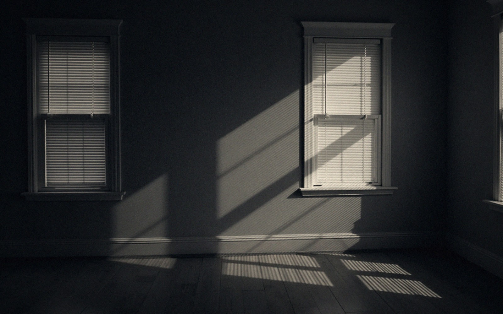 Sunlight through venetian blinds casts striped shadows across a dark, empty room